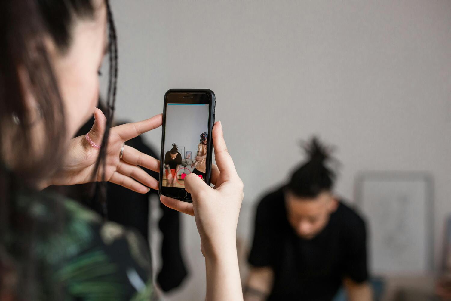 person-smartphone / Foto von Ron Lach : https://www.pexels.com/de-de/foto/person-smartphone-mobiltelefon-handy-8368375/ eine junge Frau hält ein Handy und nimmt damit ein Video von einer anderen Person auf.